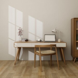 Una oficina en casa minimalista con un escritorio de madera, una computadora portátil, una lámpara, una planta y libros. Una silla de madera a juego se encuentra frente al escritorio. La luz del sol se cuela a través de las persianas y proyecta sombras en la pared, perfecta para fotografías de propiedades.